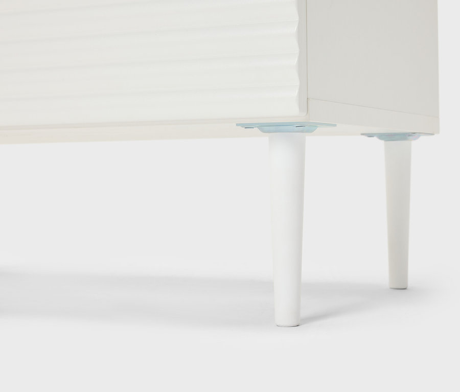 Közelkép egy fehér bútorról kúpos lábakkal.