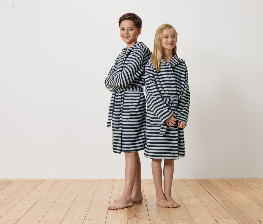 Egy fiú és egy lány háttal állnak egymásnak, csíkos fürdőköpenyben.