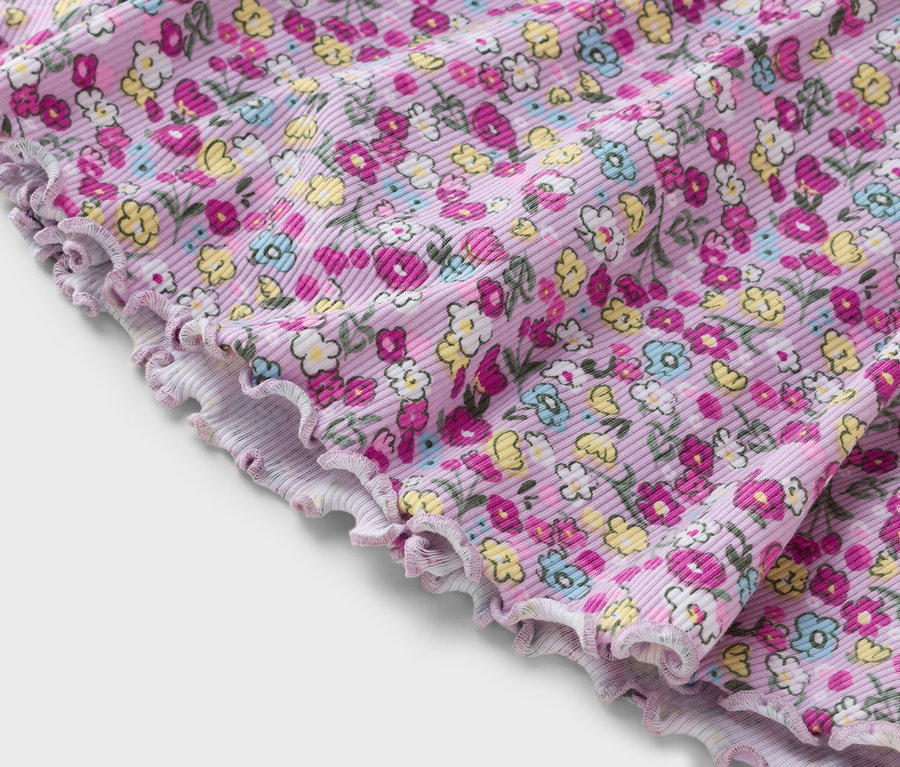 Egy virágmintás lila, bordázott anyag közeli képe.