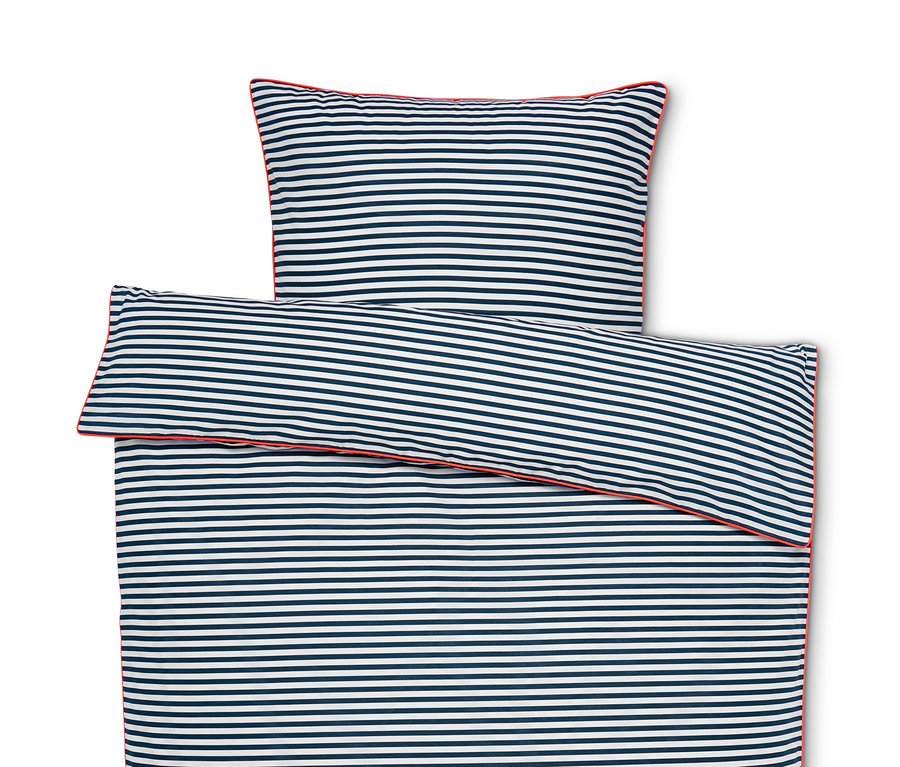 Felülnézet egy kiterített, kék-fehér csíkos, piros szegélyű renforcé ágyneműről.