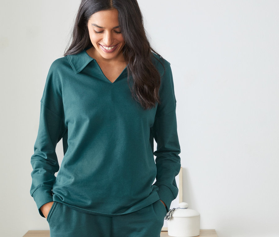 Nő visel egy zöld, TENCEL női szabadidőfelsőt és nadrágot.