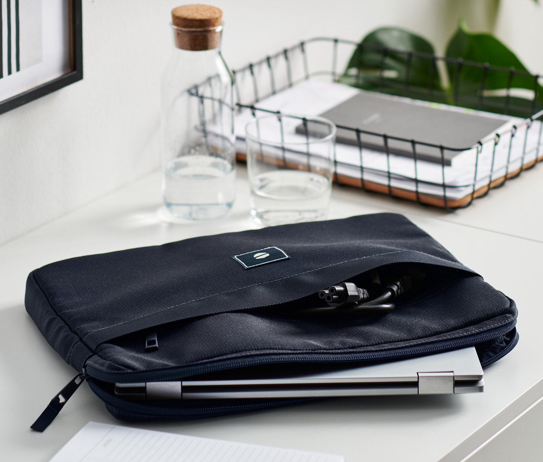 A fehér asztalon egy sötétkék laptoptartó táska látható.