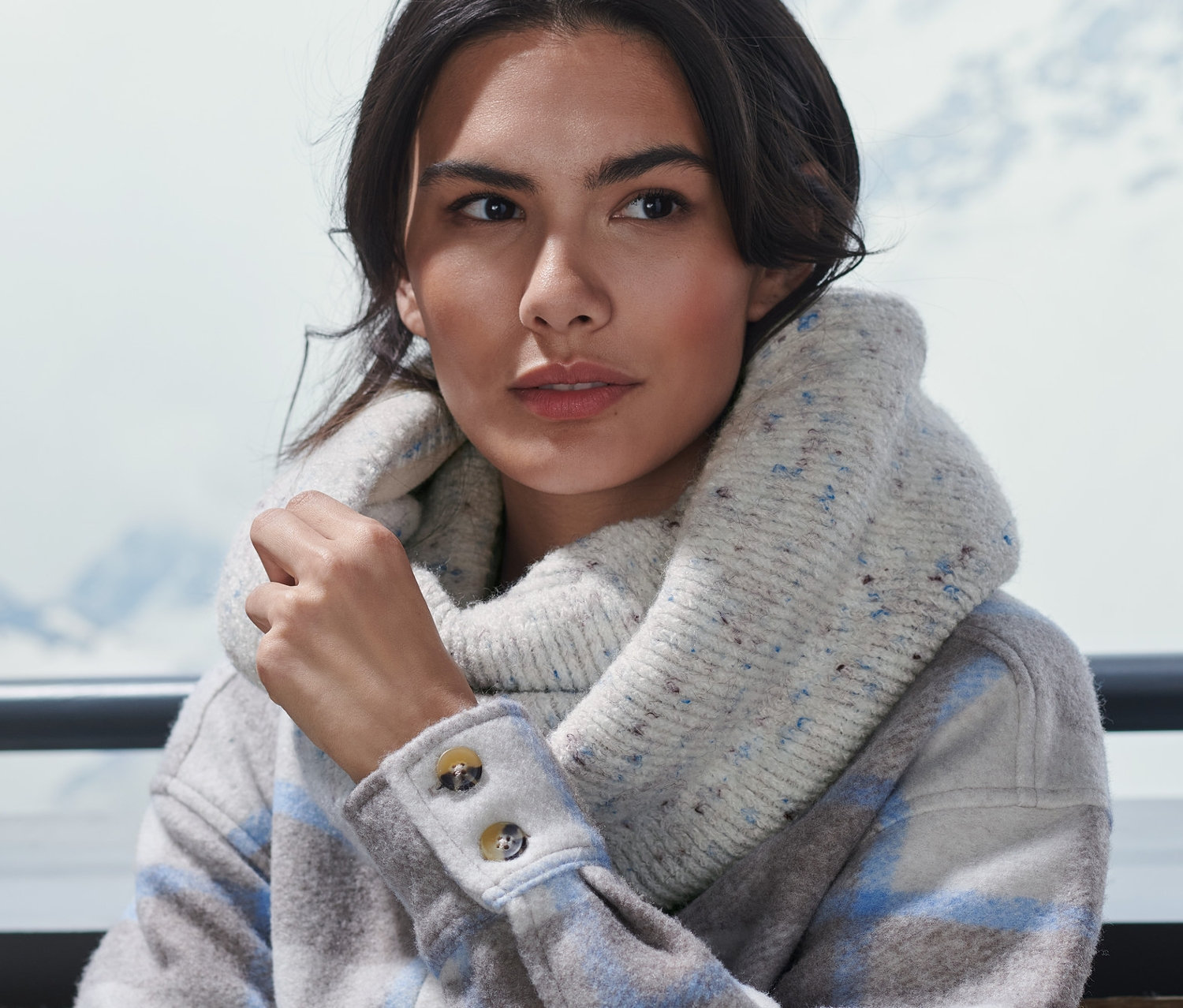 Egy nő ül kint és kötött csősálat visel.