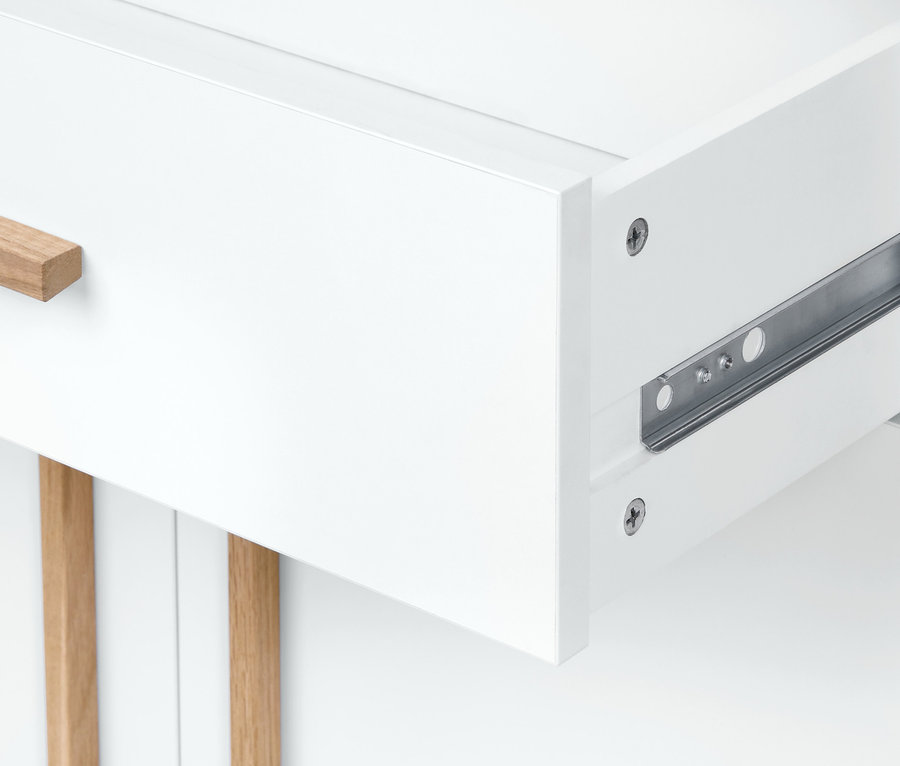 Egy fehér fürdőszobai komód kihúzott fiókjának részlete.