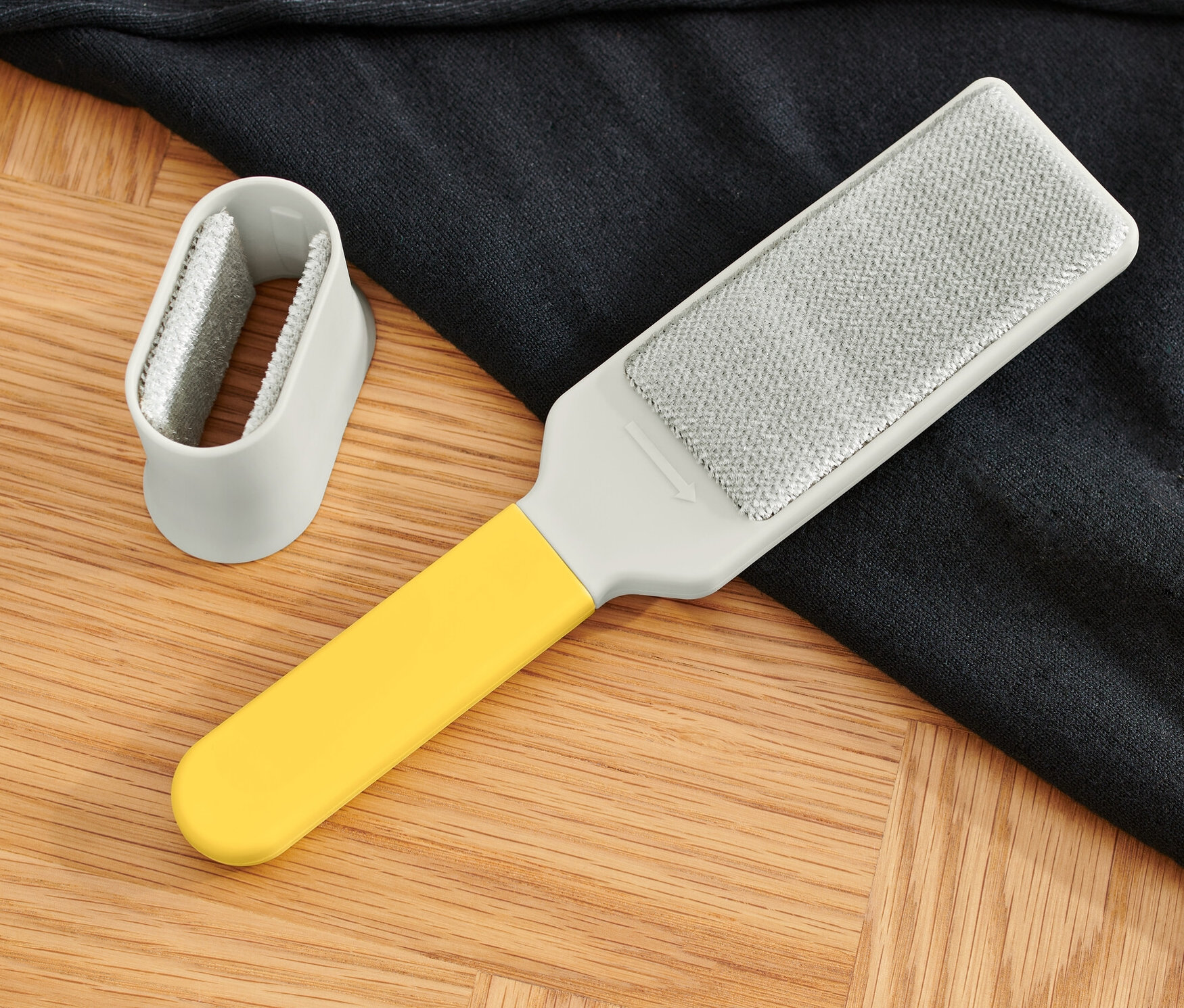 Egy ruhakefe és egy sötét pulóver fekszik egy fa padlón.