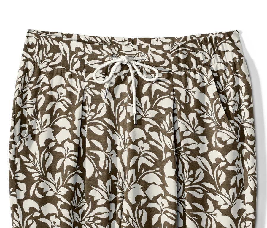 Egy nyomott mintás jerseynadrág részlete levelekkel és húzózsinórral a derékrészen.