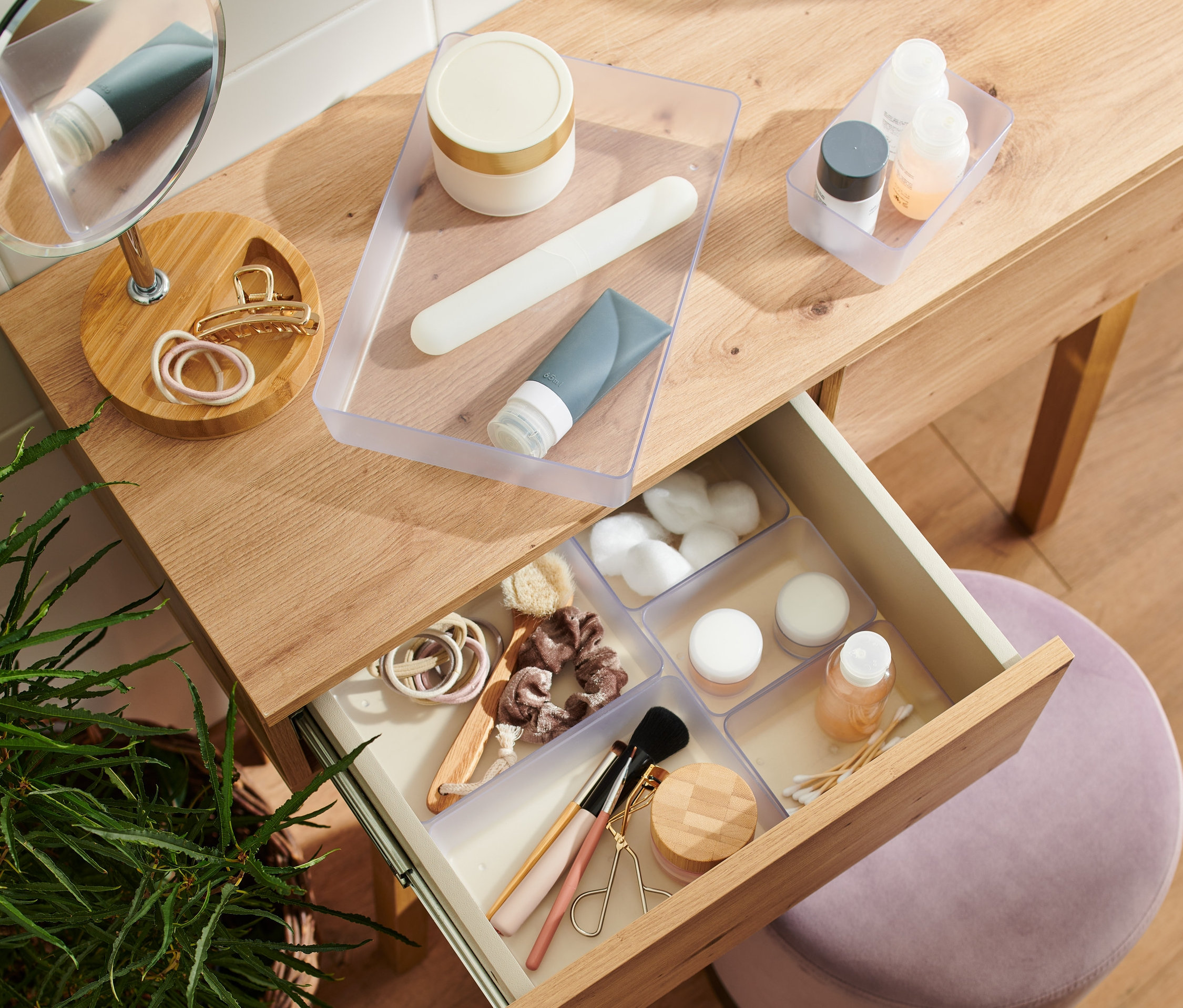 Egy fa sminkasztal nyitott fiókjában egy Rendszerező szett fiókba kozmetikumokkal.
