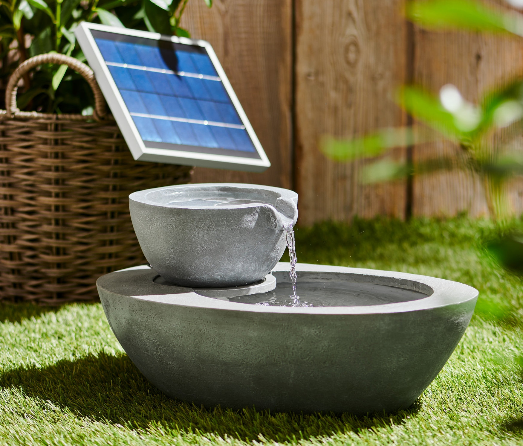 Szürke napelemes kerti szökőkút két tálkával a fűben.