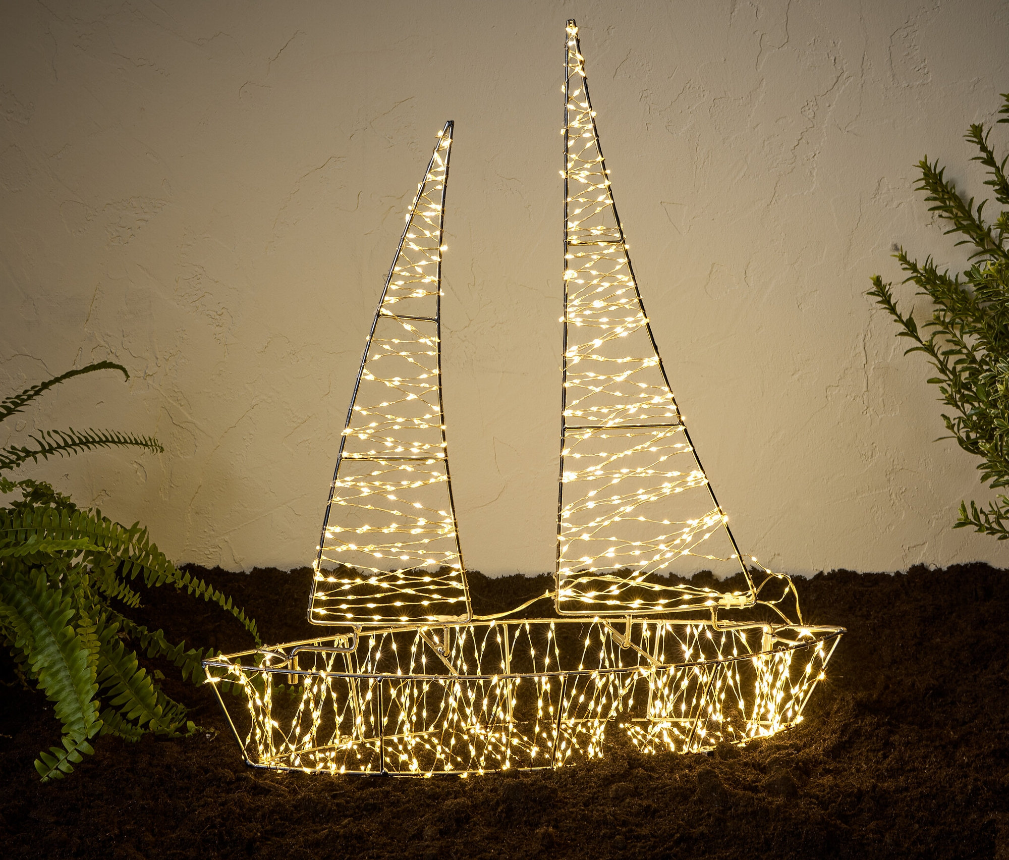 Egy megvilágított 3D-s LED-es kültéri csónak áll a földön növények mellett.