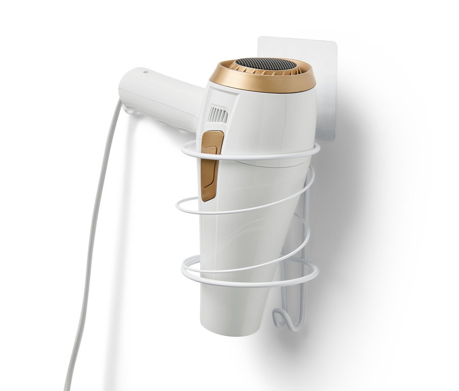 Egy fehér hajszárítótartó van rögzítve egy fehér falra, és egy fehér hajszárítót tart.