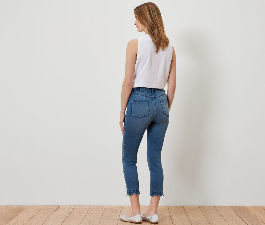 Hátulról látható nő 7/8-os, lyukhímzéses tregginget, fehér felsőt és ezüst balerinacipőt visel.