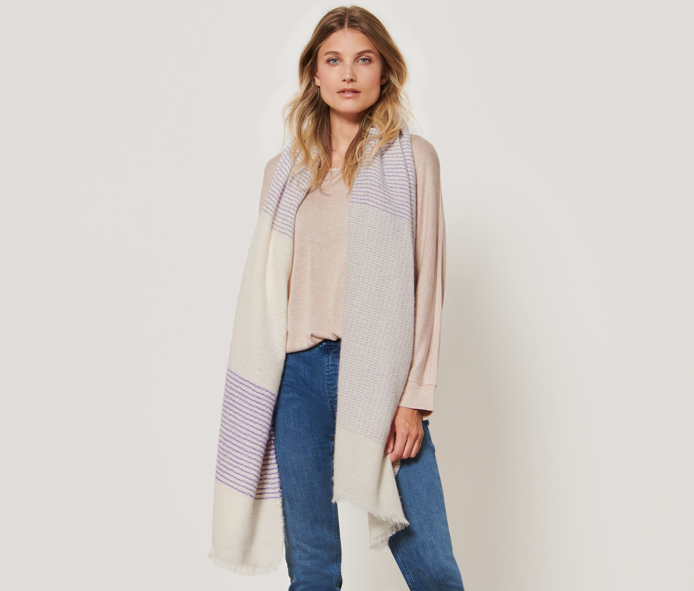 Nő pózol egy csíkos szövött sállal.