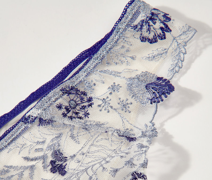 A fehér Passionata »Chloe« tanga részlete kék virágmintás hímzéssel.