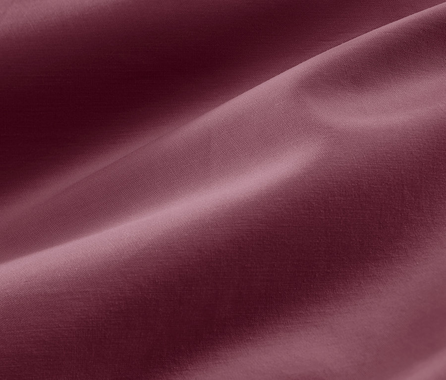 Közeli kép egy málnaszín, extra méretű pamutszatén ágynemű textúrájáról.