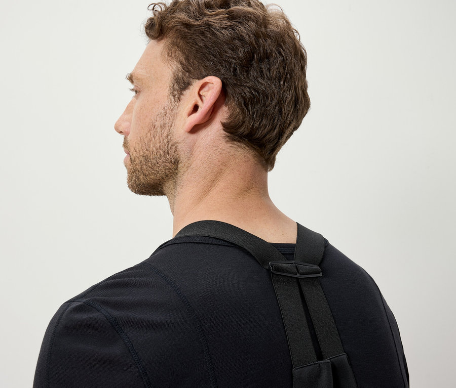 Barna hajú férfi fekete pólót és fekete pántokat visel.