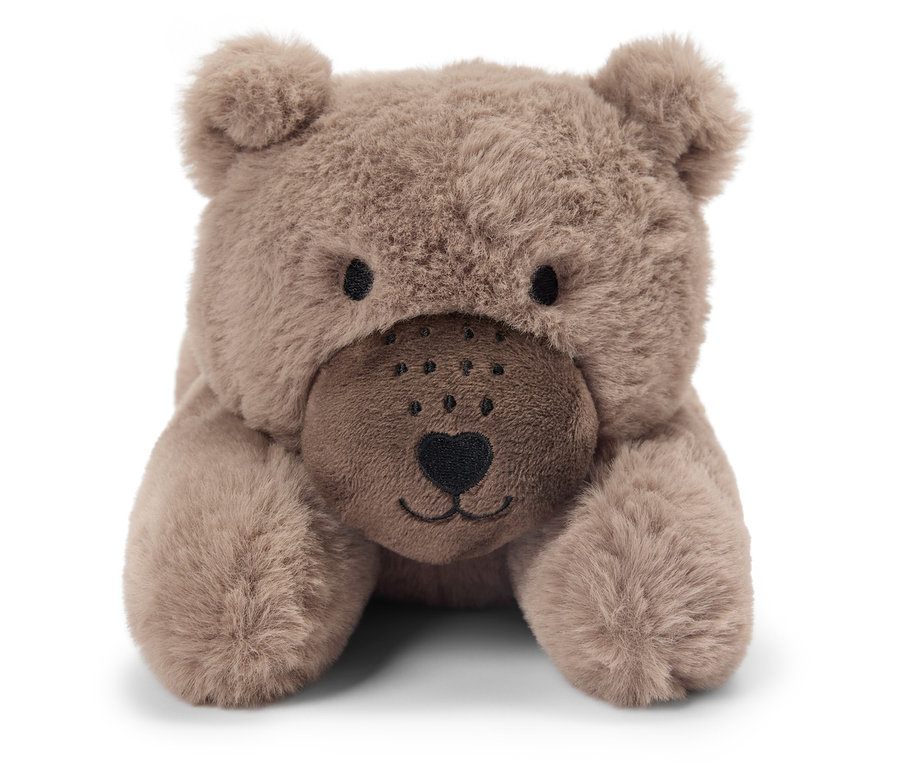 Egy barna plüssmedve fekszik a hasán.