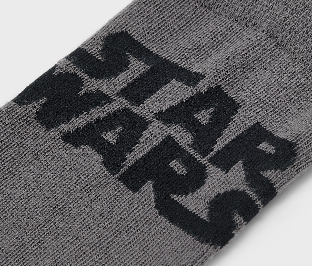 Egy szürke zokni részlete fekete STAR WARS felirattal.