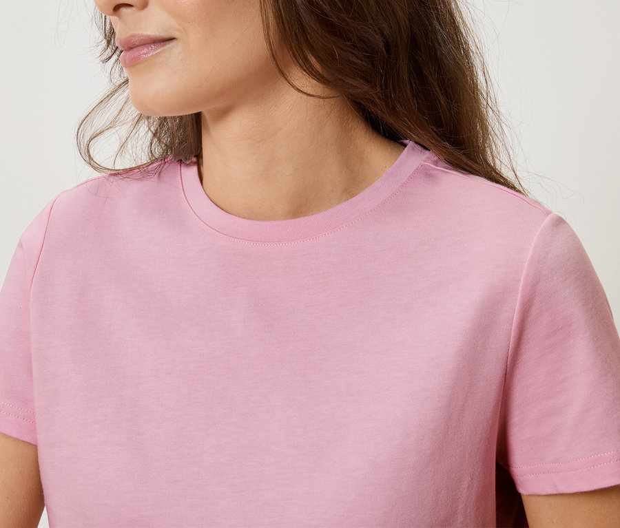 Egy rózsaszín pólót viselő nő közeli képe.