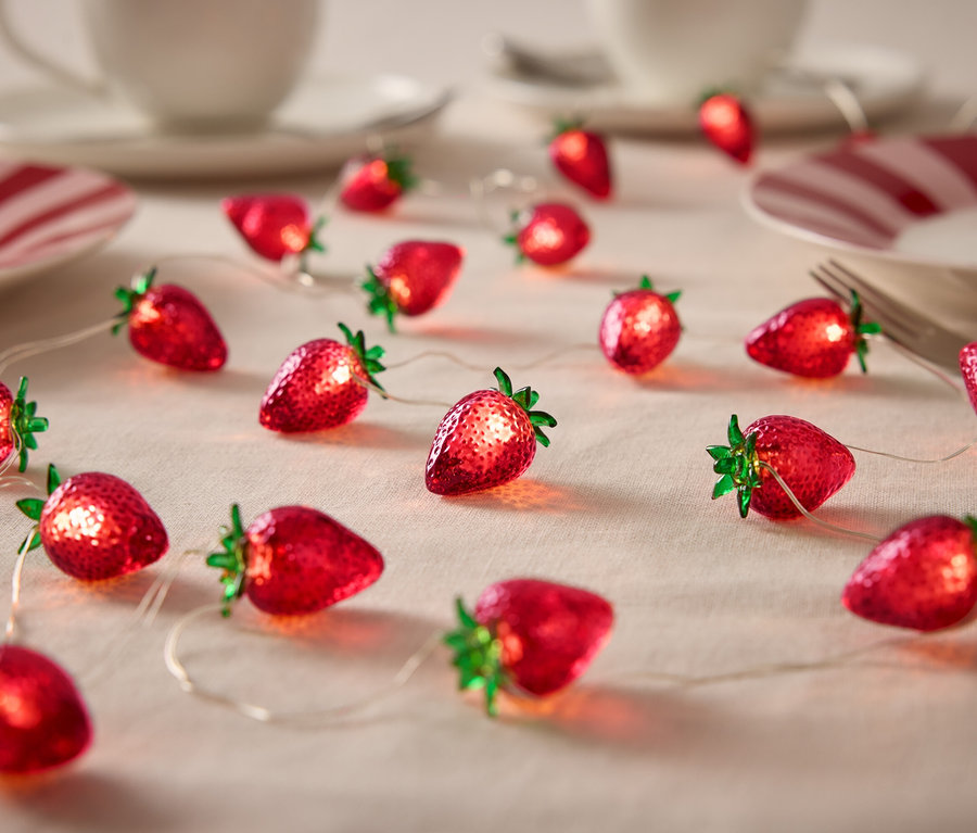 Eper alakú fényfüzér egy asztalon edényekkel.