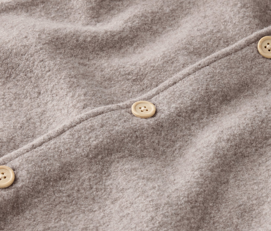 Egy szürke gyapjúszövet közeli képe három bézs gombbal.