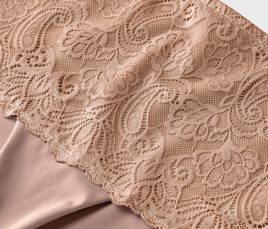 A bézs színű csipke virágmintázata egy bézs színű anyagon.