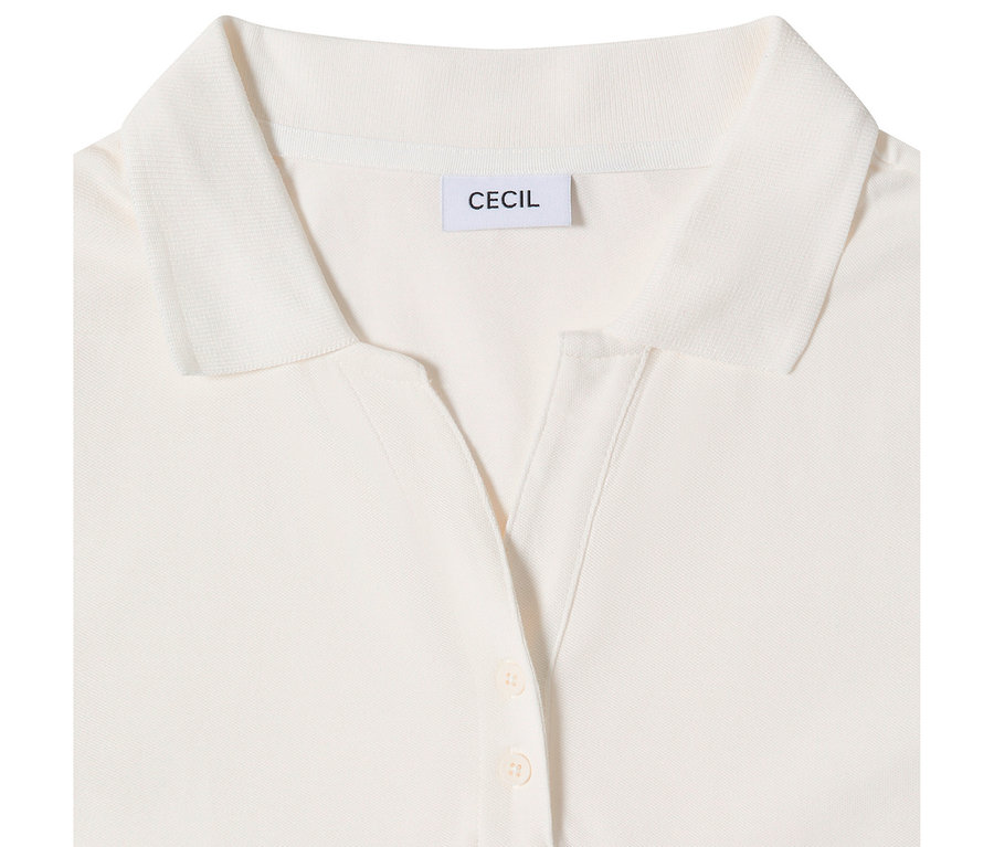 Egy fehér CECIL 3/4-es pólóing közelképe, melyen a gallér, egy V-nyakú gomboláspánt két világos gombbal és a 'CECIL' márkajelzés látható.