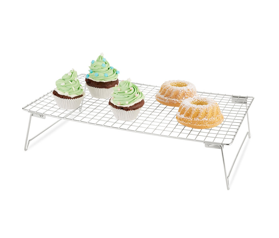 Három zöld díszítésű muffin és két porcukorral meghintett kuglóf a háromszintes hűtőrácson.