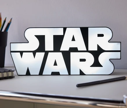 Az asztalon egy világító Star Wars felirat áll, mellette egy ceruza, egy notesz és egy pohár színes ceruza.