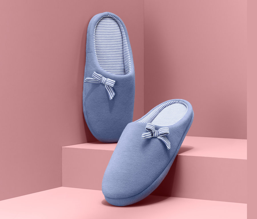 Két kék, csíkos bélésű, masnis női házicipő rózsaszín lépcsőn.