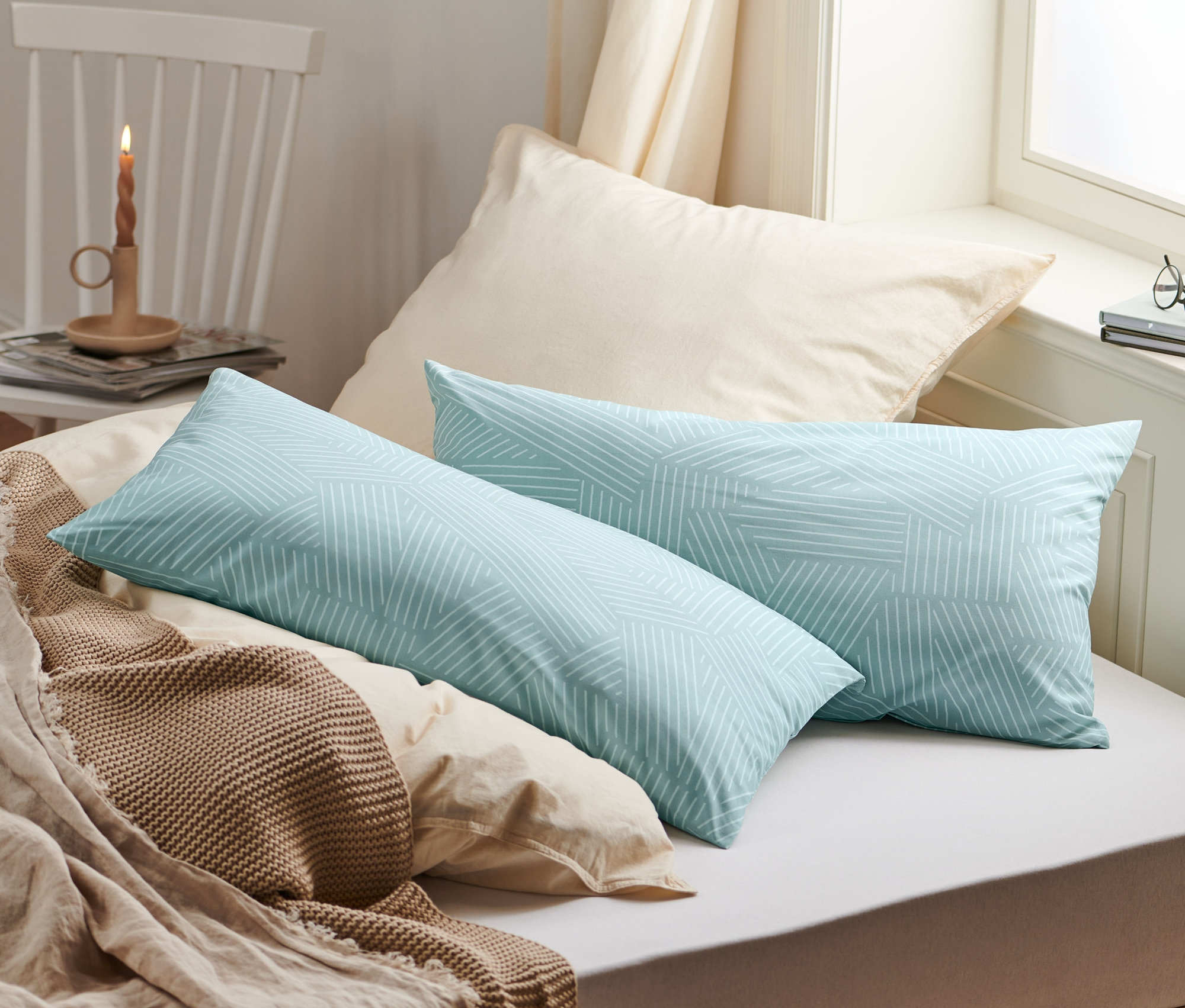 Két geometrikus mintás renforcé párnahuzat fekszik az ágyon.