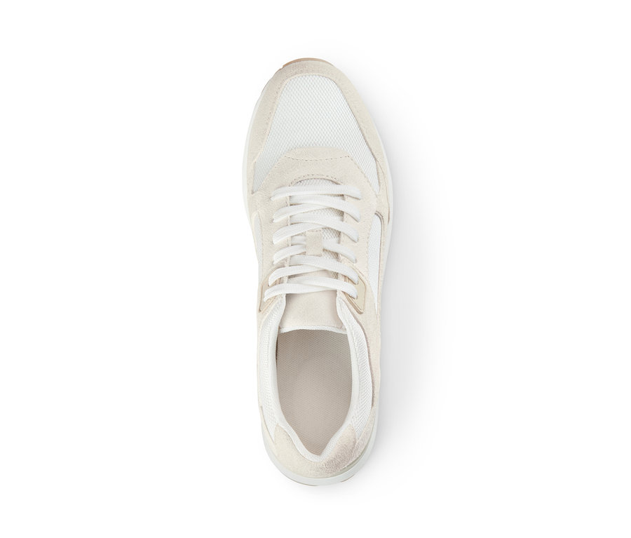 Egy krémszínű női velúrbőr sneaker cipő közelképe fehér háttéren.
