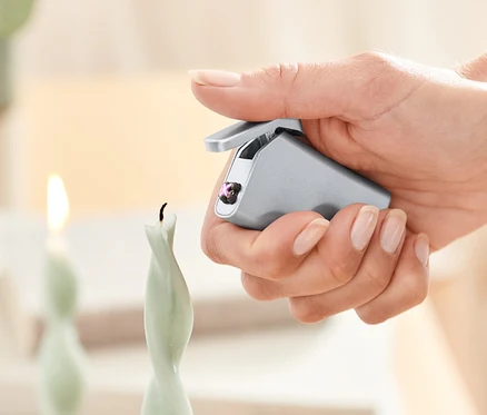 Egy nő gyertyát gyújt egy elektromos öngyújtóval.