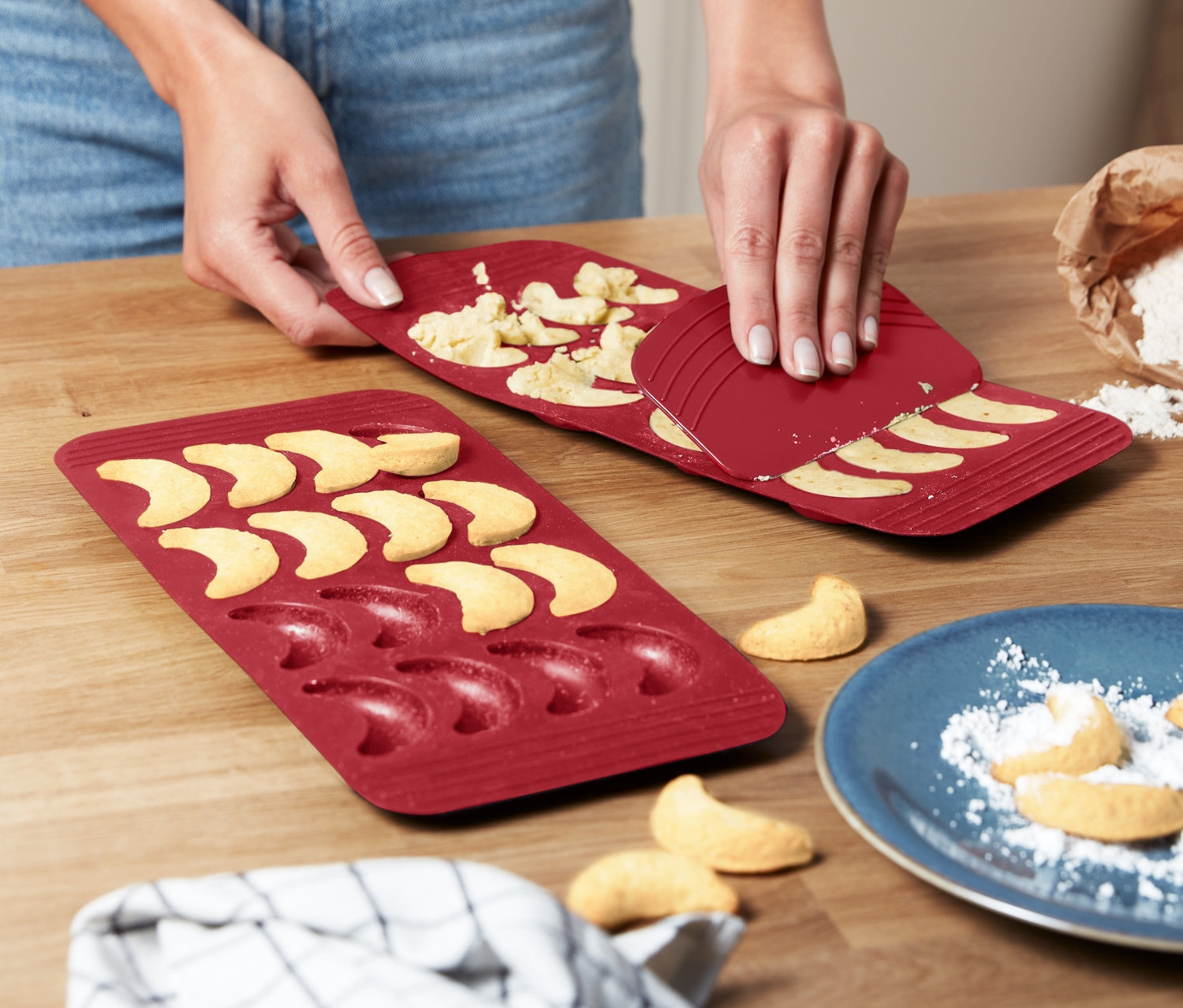 Nő veszi ki a vaníliás kifliket a 2 szilikon vaníliás kifli sütőformából.