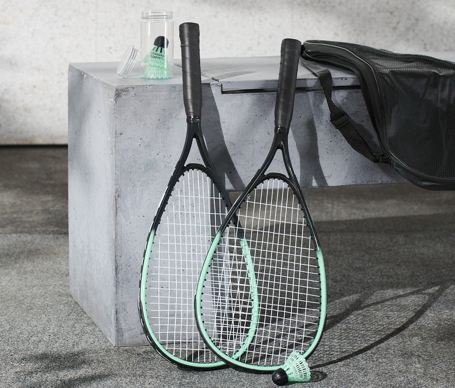 Két ütő és egy tartály tollaslabda a gyorstollaslabda készletből betonon.