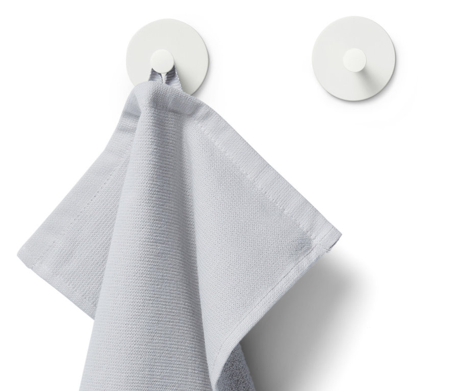 Egy világosszürke törölköző lóg az egyik fehér 2 akasztó egyikén.