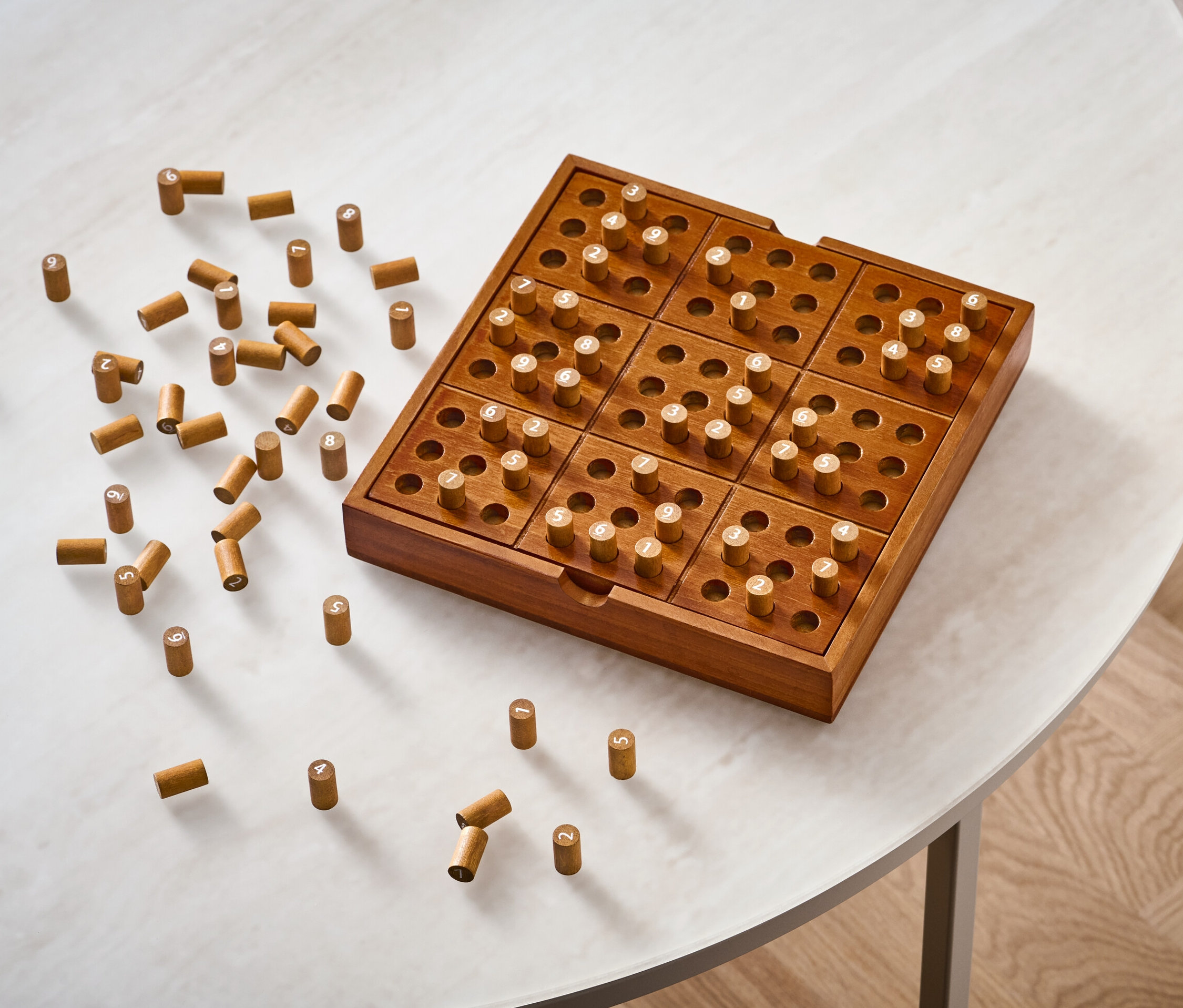 Fa Sudoku társasjáték csapokkal egy fehér asztalon.