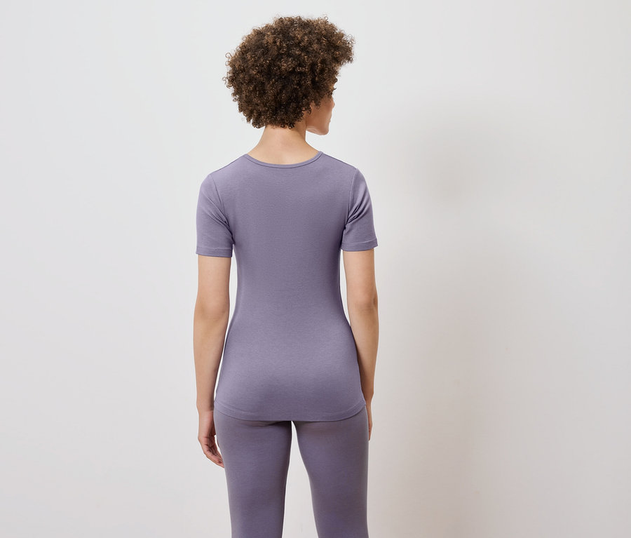 Hátulról látható egy göndör hajú nő, aki lila pólót és leggingset visel.