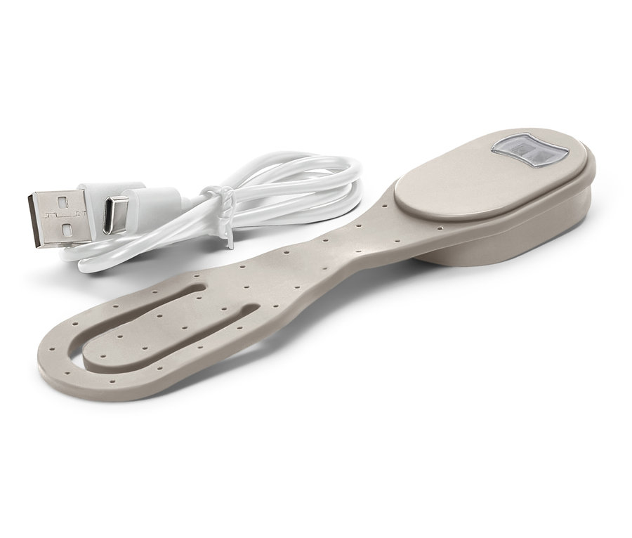 Egy bézs könyvklipsz lámpával és a hozzá tartozó USB töltőkábellel fekszik egy fehér háttéren.