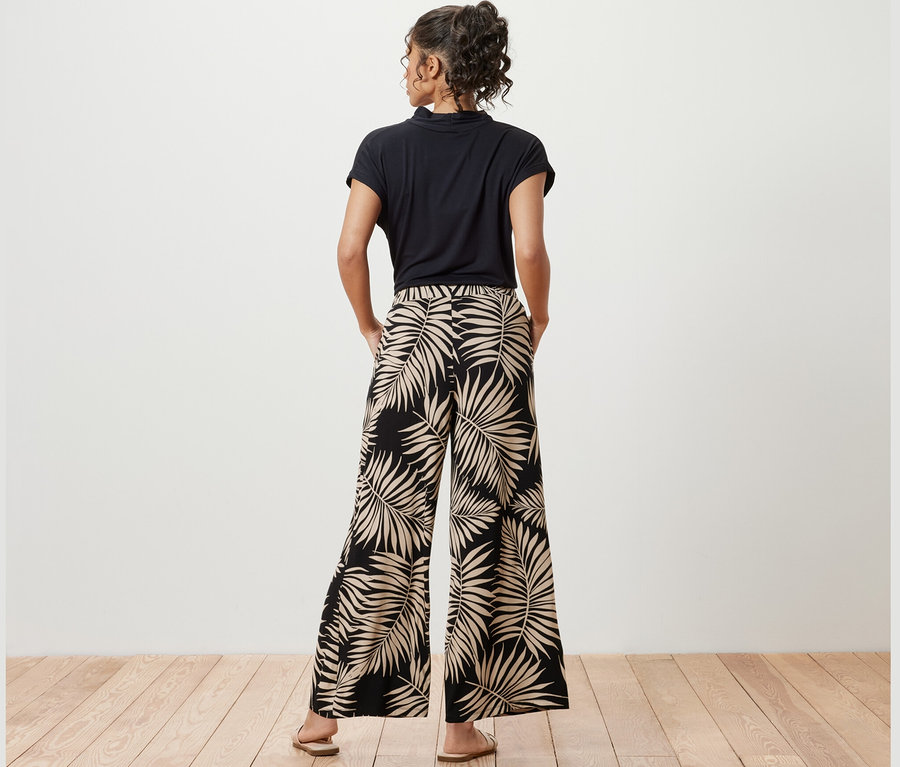 Nő pózol nyomott mintás palazzo nadrágban.