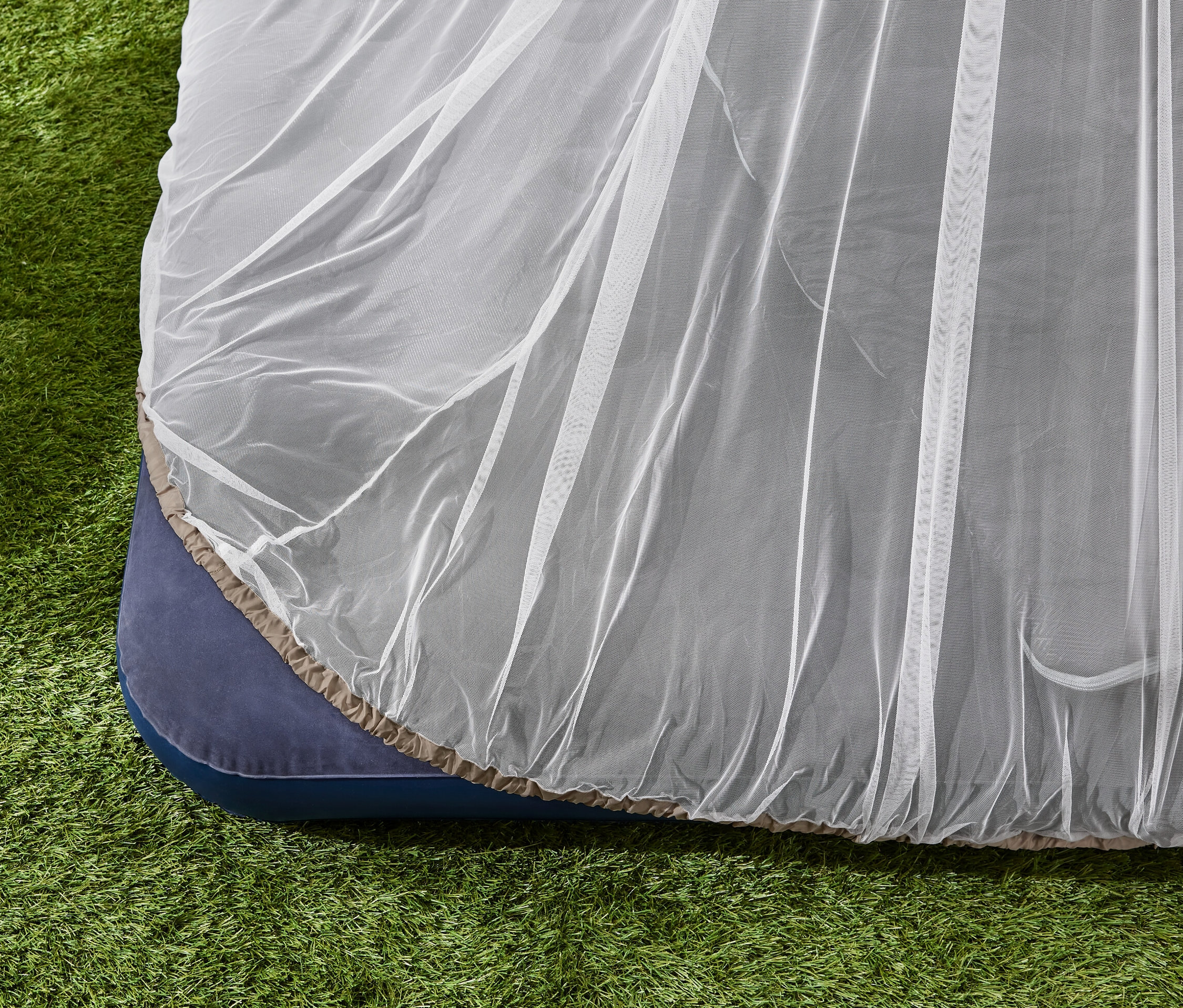 Baldachin szúnyogháló egy matracon a fűben.