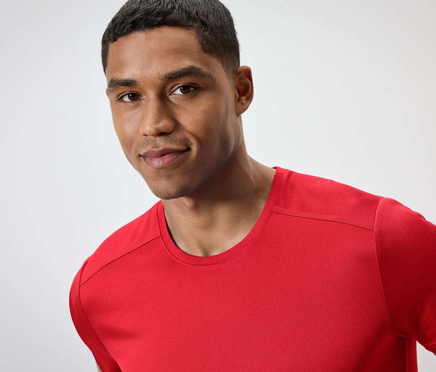 Portré egy rövid hajú férfiról piros pólóban.