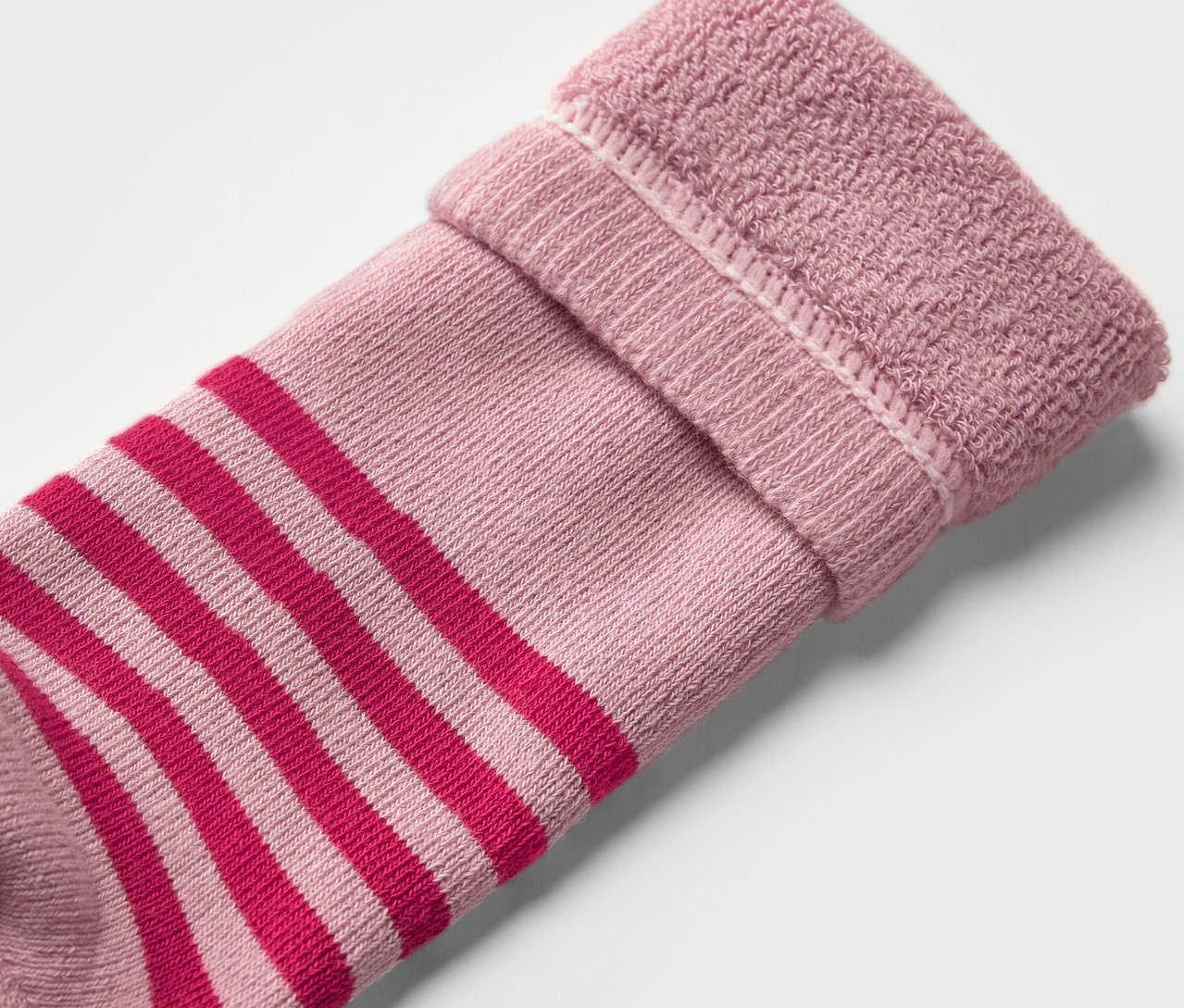 Egy virágos gumicsizma zokni részlete (2 pár). A zokni rózsaszín, piros csíkokkal és felhajtott szegéllyel rendelkezik.