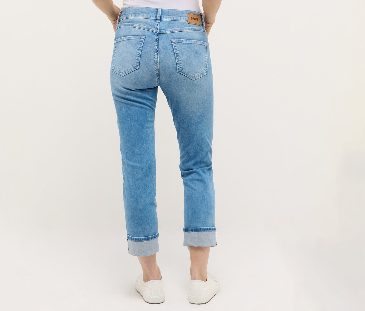 Egy személy Angels denim »Cira Boho« farmert és fehér cipőt visel.