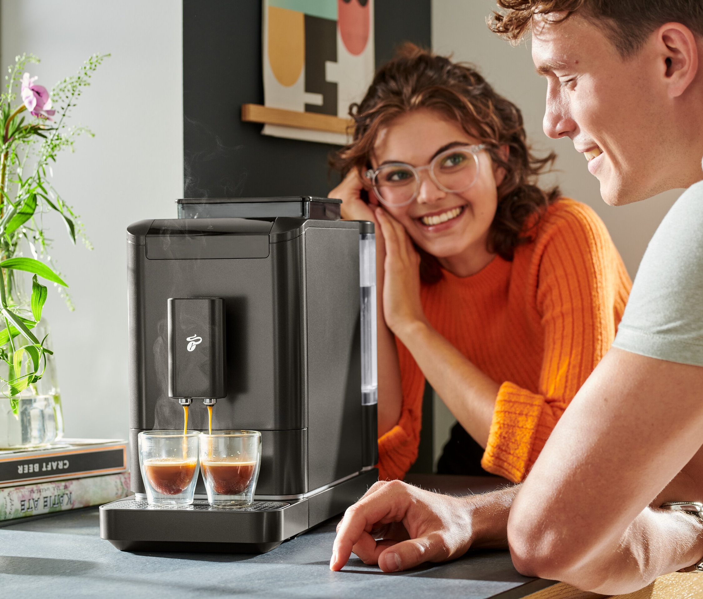 Két ember nézi, ahogy a kávé folyik a »Esperto2 Caffè« automata kávéfőzőből két pohárba.