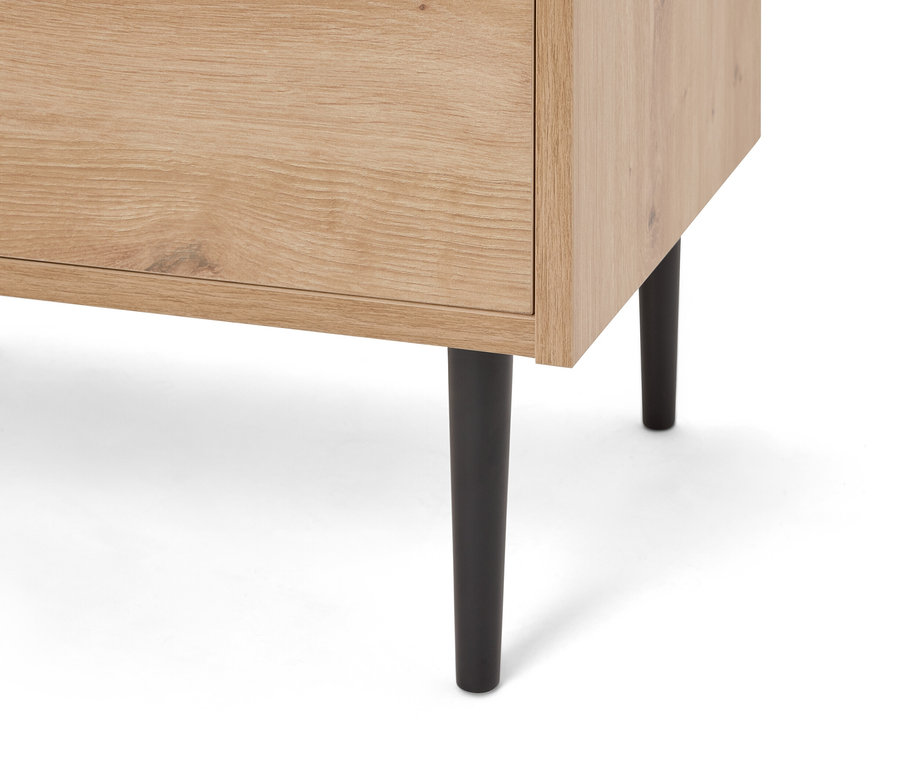 Egy világosbarna fa szekrény közeli képe fekete lábakkal.