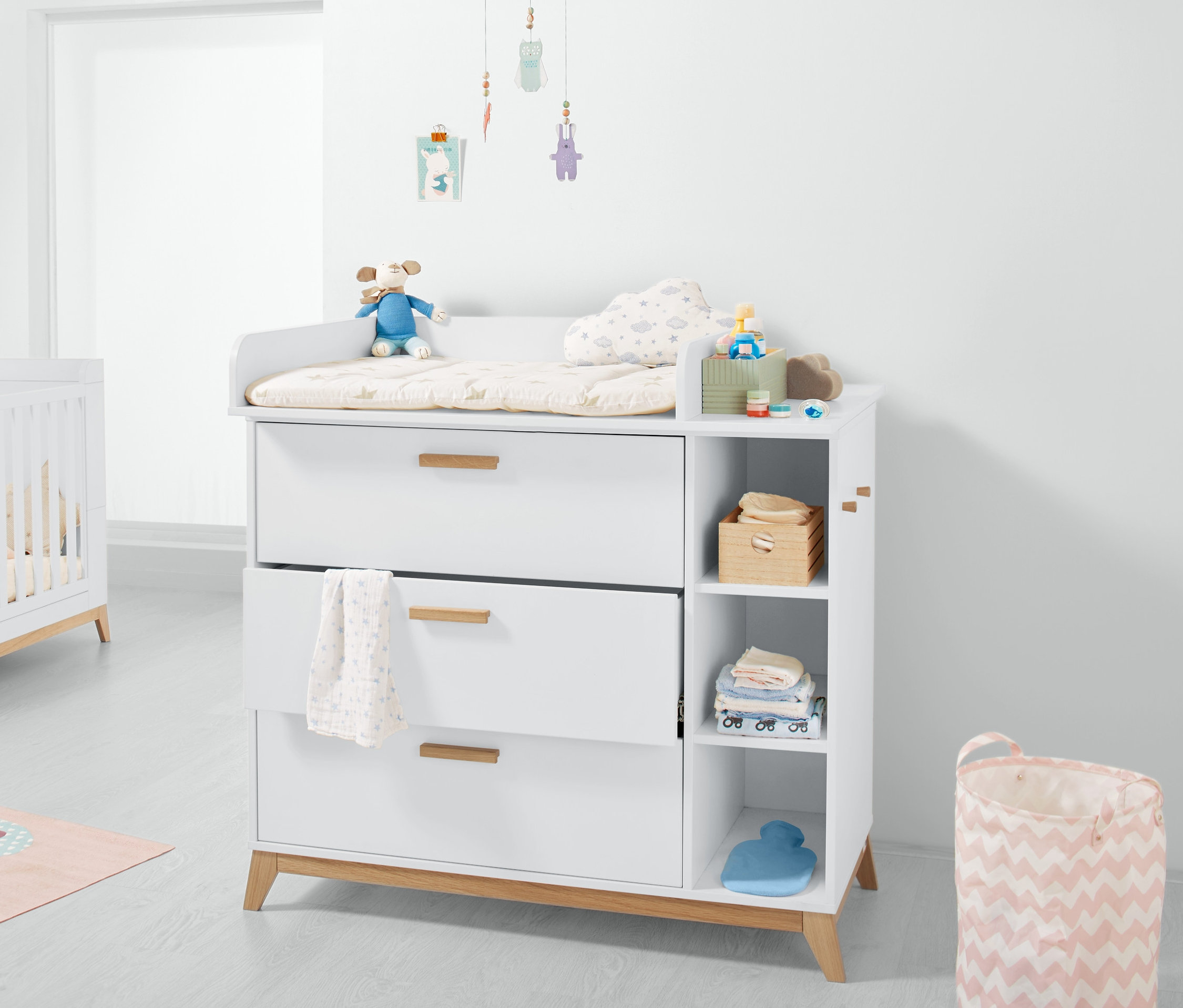 Fehér pelenkázó komód három fiókkal és nyitott polcokkal.