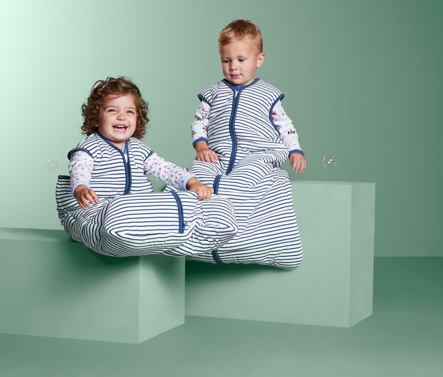 Két gyerek ül kockákon csíkos kisgyerek hálózsákokban.