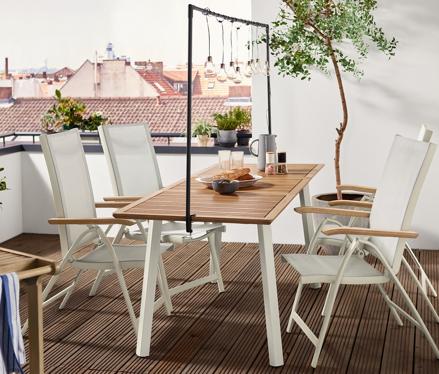 Négy »Liska« összecsukható szék áll egy fa asztalnál. Az asztal fölött egy asztali dekor állvány lóg LED-es égősorral.