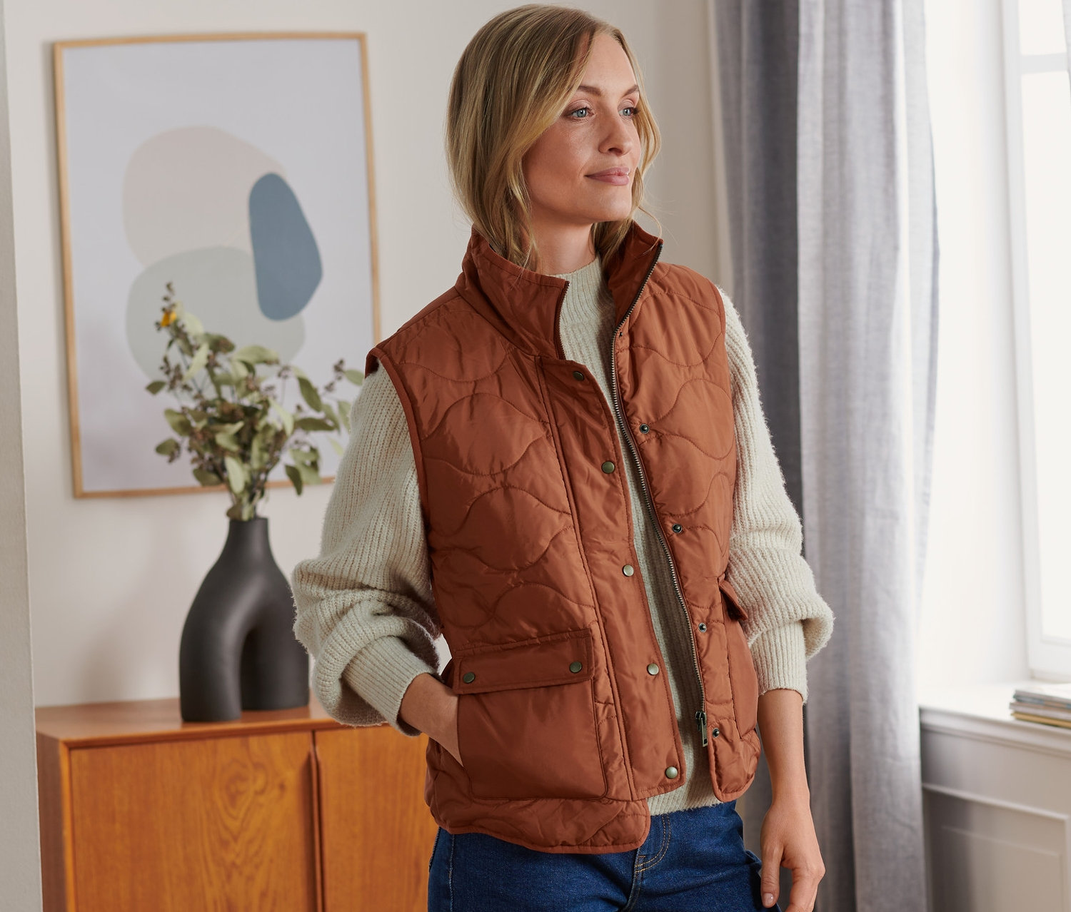 Nő visel barna, állógalléros steppelt mellényt.