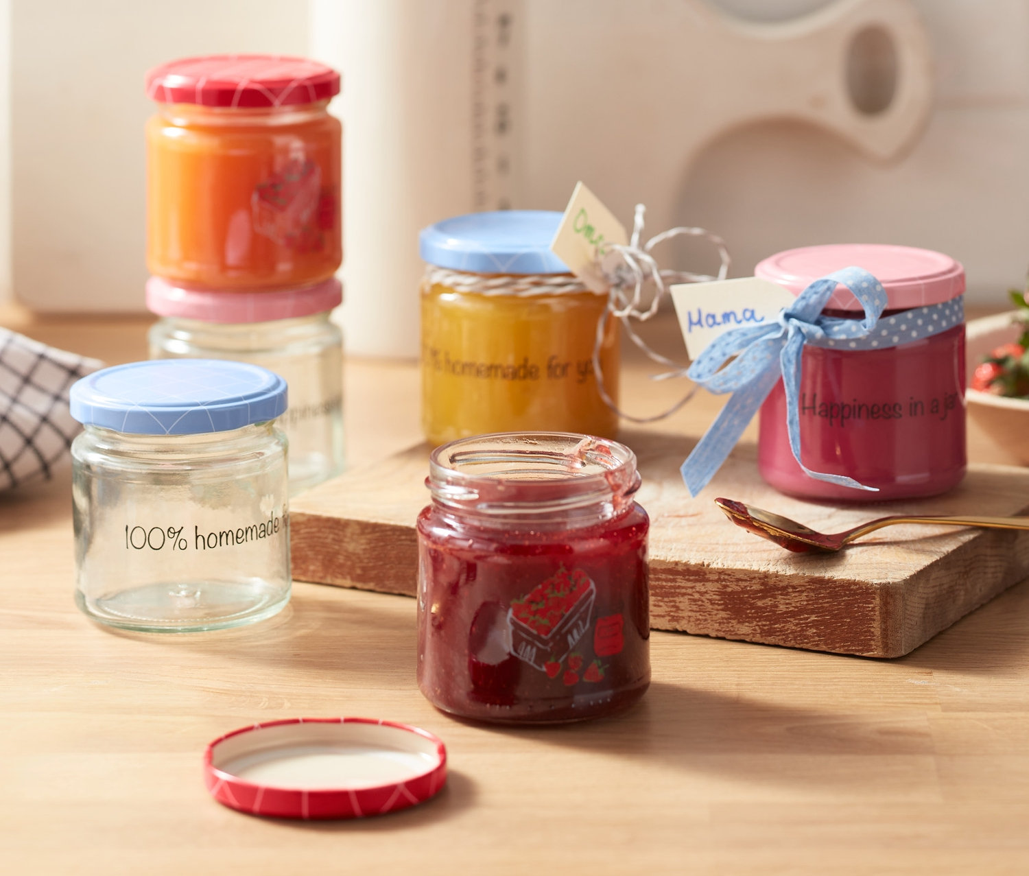 Hat darab csavaros fedéllel ellátott befőttes üveg házi lekvárokkal és címkékkel egy fa asztalon.